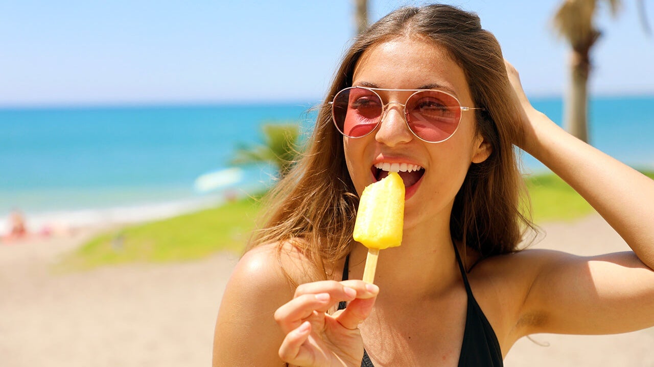 Mulher jovem saboreando um delicioso picolé na praia