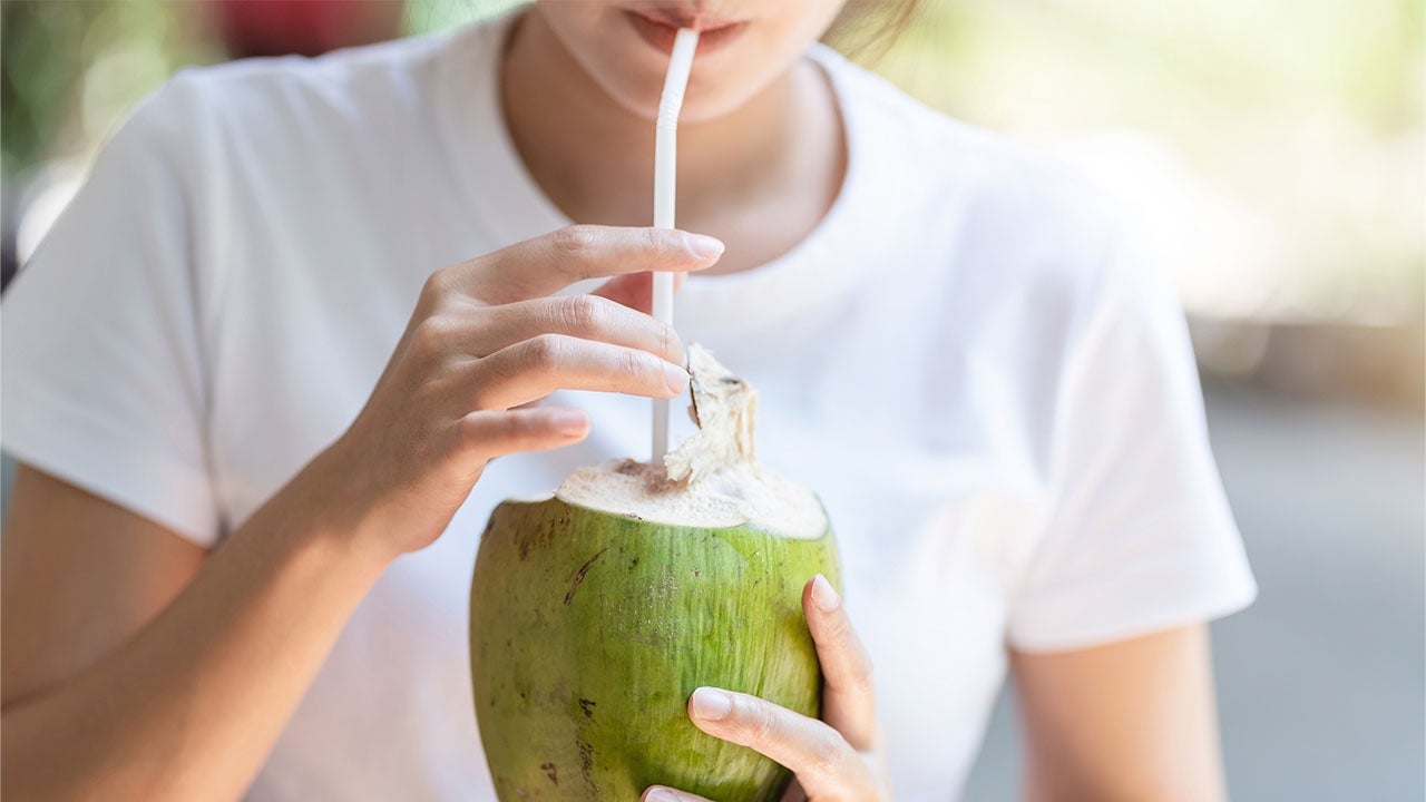 Pessoa se refrescando no verão depois de descobrir os benefícios da água de coco