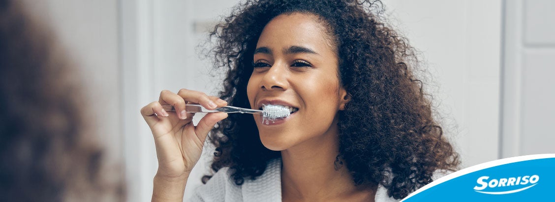 Mulher olhando no espelho para escovar os dentes